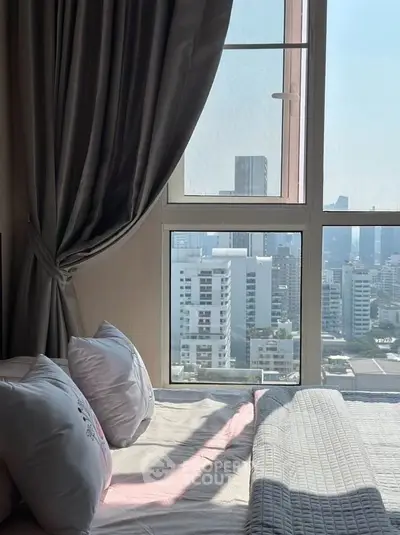Cozy bedroom with city view, featuring large windows and elegant curtains.