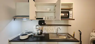 Modern kitchen with open cabinets, microwave, and sleek appliances in a compact layout.
