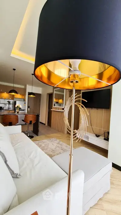 Modern living room with stylish decor and open kitchen layout, featuring elegant lighting and contemporary furniture.