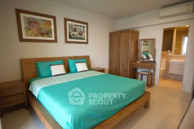 Cozy bedroom with wooden furniture and ensuite bathroom, featuring vibrant teal bedding and decorative artwork.