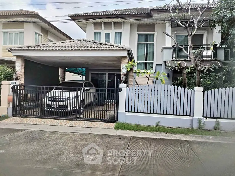 Modern two-story house with carport and gated driveway in suburban neighborhood.
