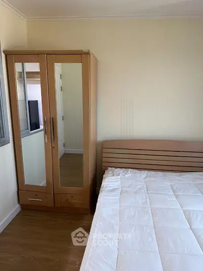 Cozy bedroom with wooden wardrobe and comfortable bed in modern apartment.