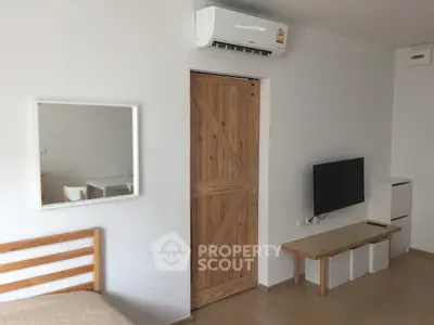 Modern bedroom with minimalist decor, featuring a wooden sliding door and wall-mounted TV.