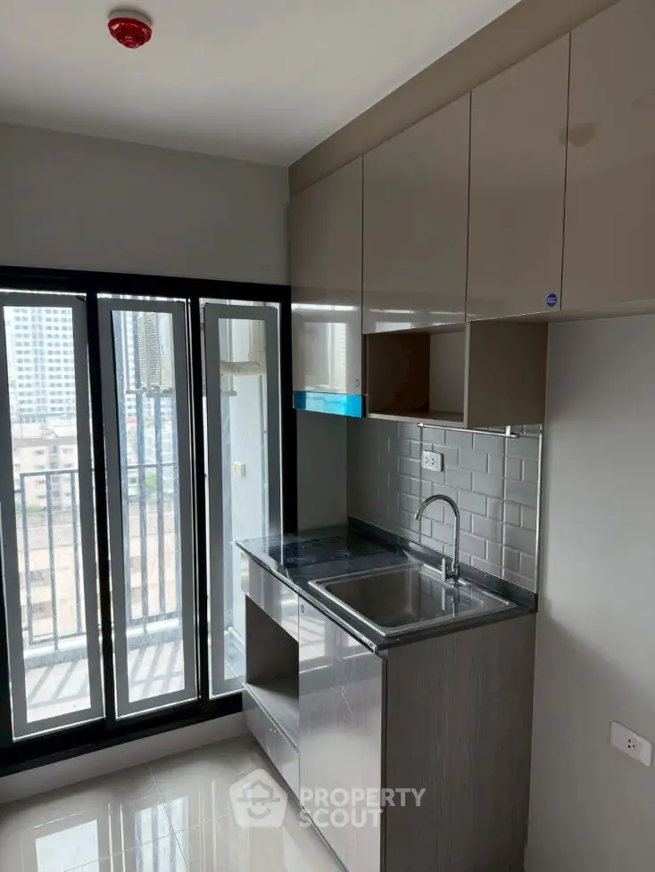 Modern kitchen with sleek cabinetry and city view from balcony.
