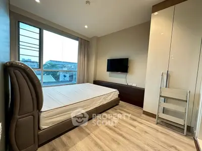 Modern bedroom with sleek design, large window, and mounted TV in a stylish apartment.