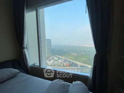 Stunning bedroom view with large window overlooking cityscape and greenery