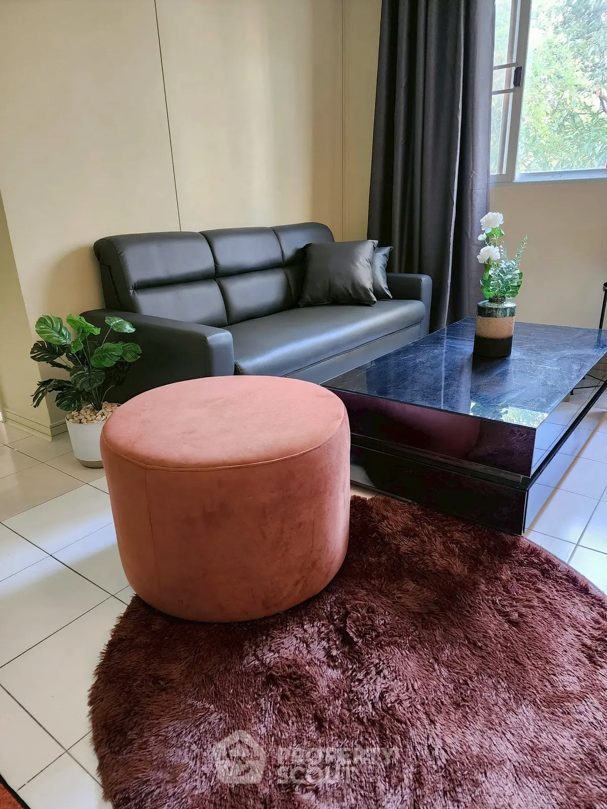 Modern living room with sleek black sofa, plush ottoman, and stylish decor for a cozy ambiance.