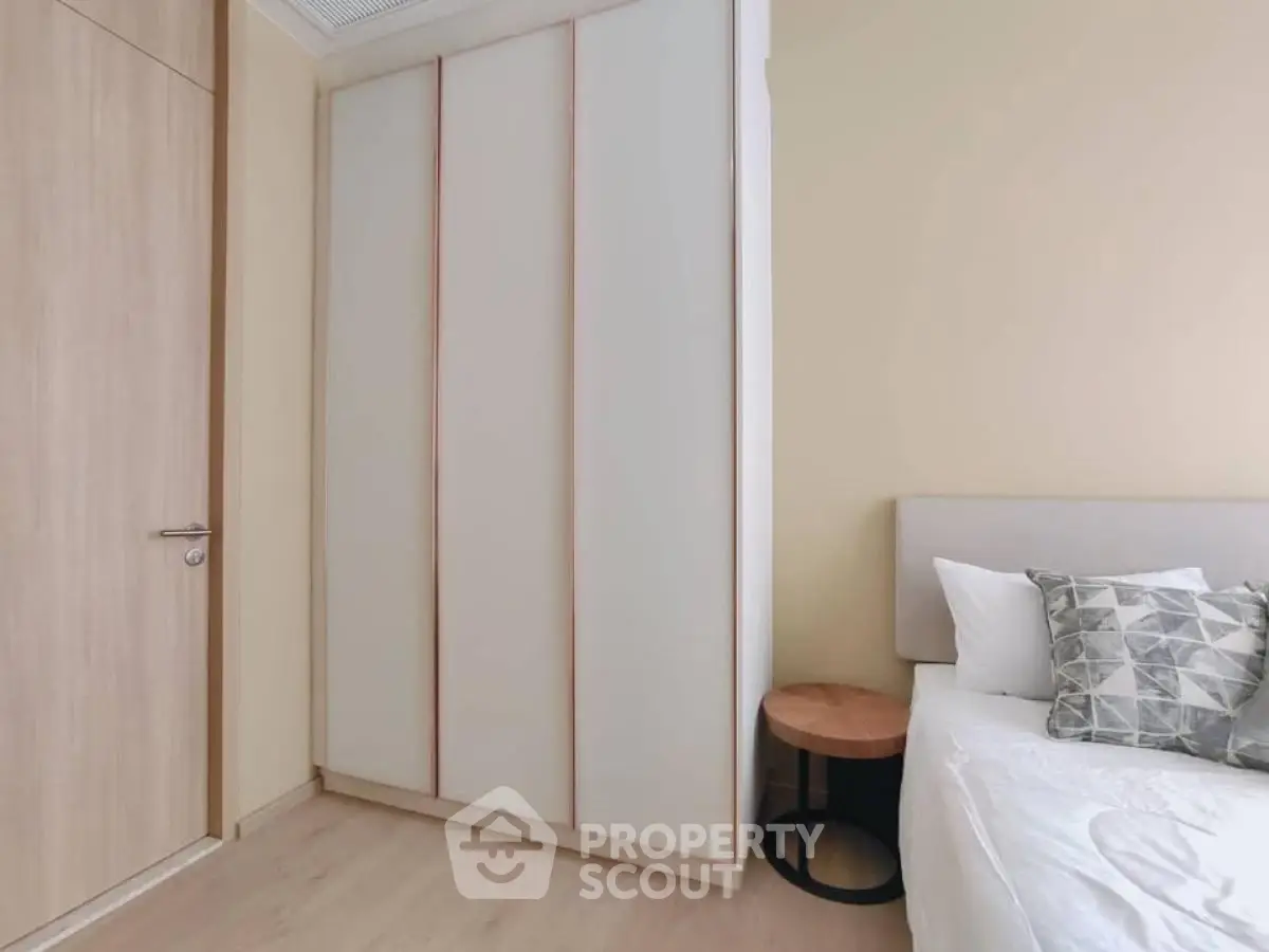 Modern bedroom with sleek wardrobe and cozy bed setup.