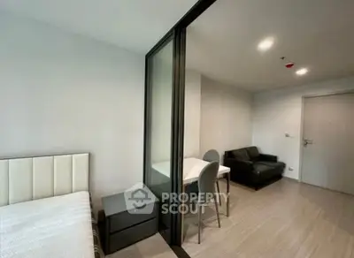 Modern studio apartment with glass partition, cozy living area, and sleek furnishings.