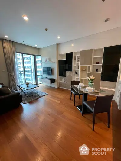 Modern living room with wooden floors, stylish furniture, and large windows offering city views.