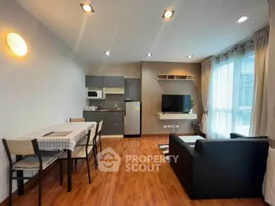Modern open-plan living room with dining area and kitchenette, featuring sleek furniture and bright lighting.