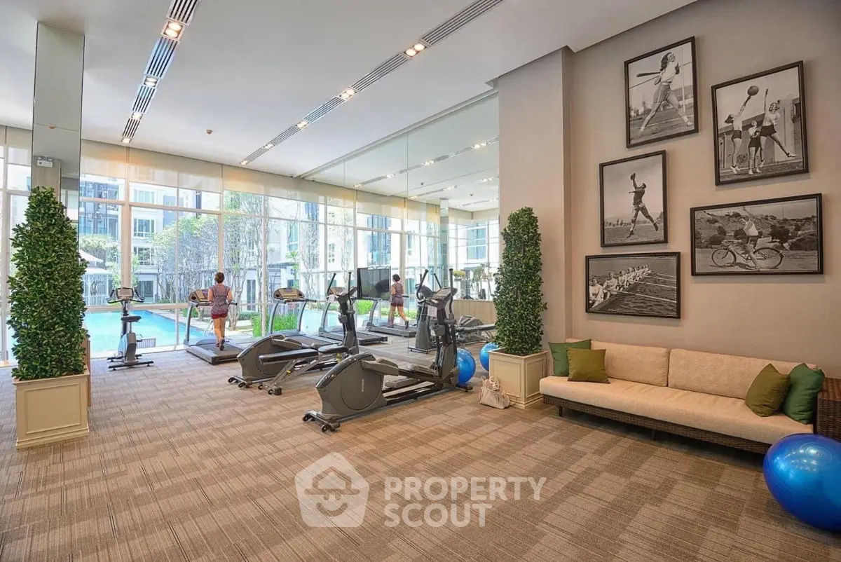 Luxurious gym with modern equipment and pool view in upscale residential building.
