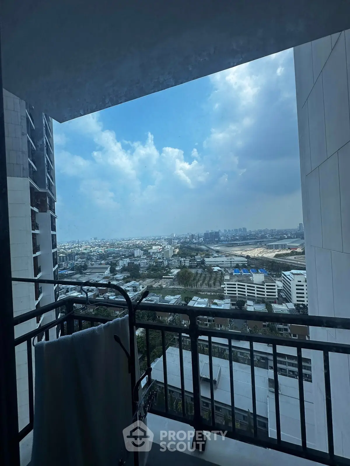 Stunning cityscape view from a high-rise balcony with clear blue skies.