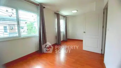 Spacious empty room with wooden flooring and large windows for natural light.