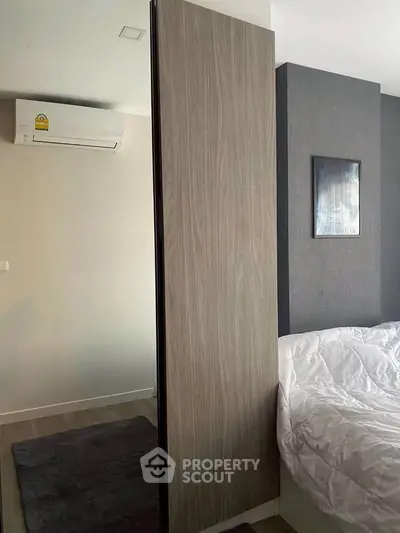 Modern bedroom with sleek design and air conditioning, featuring a stylish wooden wardrobe and cozy bedding.