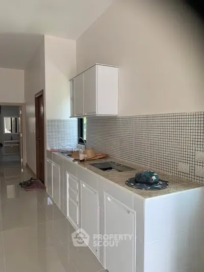 Modern kitchen with sleek white cabinets and tiled backsplash in a contemporary home.