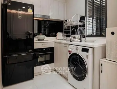 Modern kitchen with sleek appliances and washing machine in stylish interior.