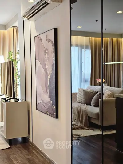 Modern living room with elegant decor and large mirror reflecting cozy seating area.
