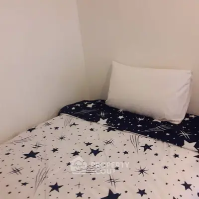 Cozy bedroom with star-themed bedding and a white pillow against a plain wall.