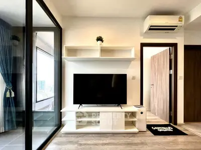 Modern living room with sleek TV stand and air conditioning unit, featuring a glass partition and wooden flooring.