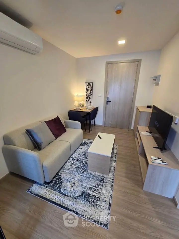 Modern living room with cozy sofa, stylish decor, and flat-screen TV in a compact apartment setting.