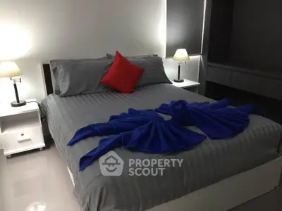 Modern bedroom with stylish decor and elegant lighting, featuring a neatly arranged bed with vibrant accents.