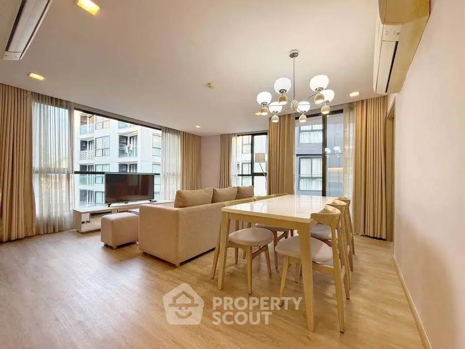 Spacious modern living room with elegant dining area and large windows offering city views.