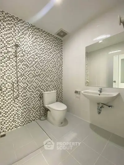 Modern bathroom with sleek fixtures and stylish mosaic tile wall design.