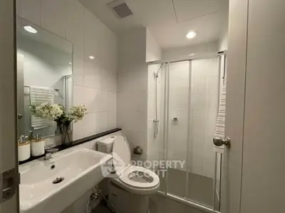 Modern bathroom with sleek fixtures and glass shower enclosure in a contemporary home.