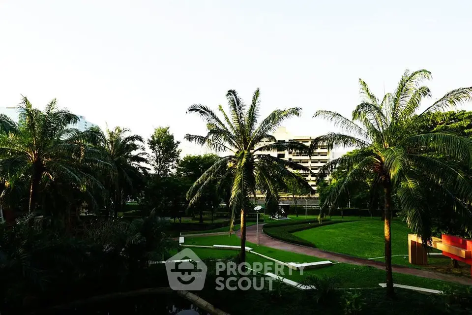 Lush garden view with palm trees and modern building backdrop, perfect for serene living.