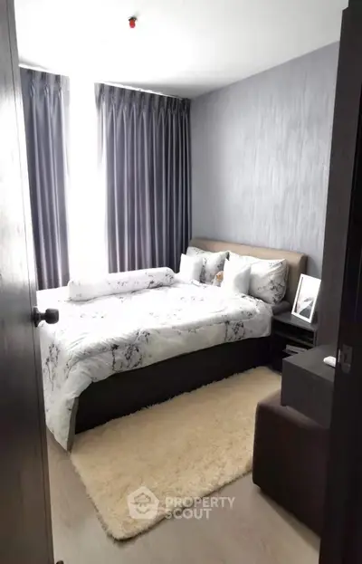 Cozy bedroom with modern decor and natural light, featuring a plush rug and elegant curtains.