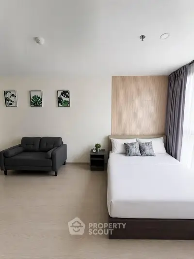 Modern bedroom with stylish decor and natural light, featuring a cozy bed and elegant armchair.