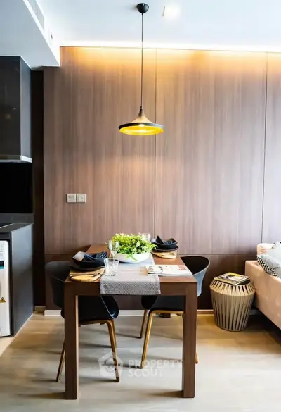 Modern dining area with stylish lighting and wooden accents in a cozy apartment setting.