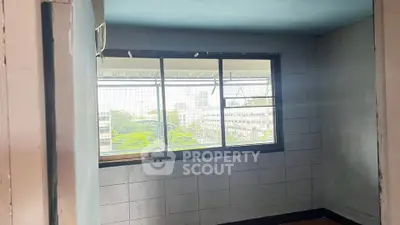Spacious room with large window offering cityscape views, ideal for natural light and urban living.