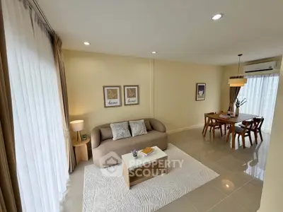 Modern living room with elegant decor and dining area, featuring neutral tones and natural light.