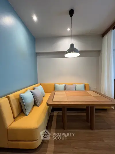 Stylish modern living room with cozy yellow sofa and wooden table under elegant pendant light.