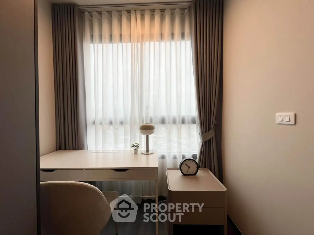 Cozy study room with modern desk and chair, featuring a large window with elegant curtains.