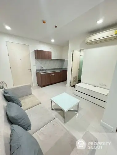 Modern studio apartment with integrated living space, featuring a sleek kitchenette, comfortable seating area, and bright white interiors for a spacious feel.