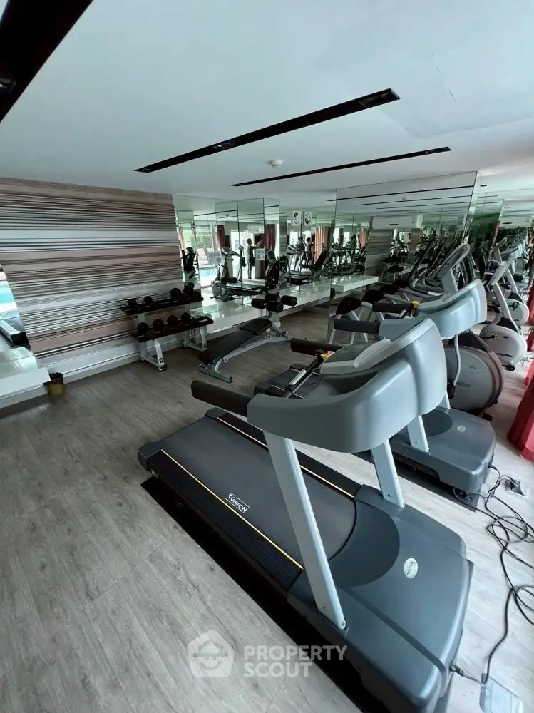 Modern gym with treadmills and weights in a stylish apartment complex.