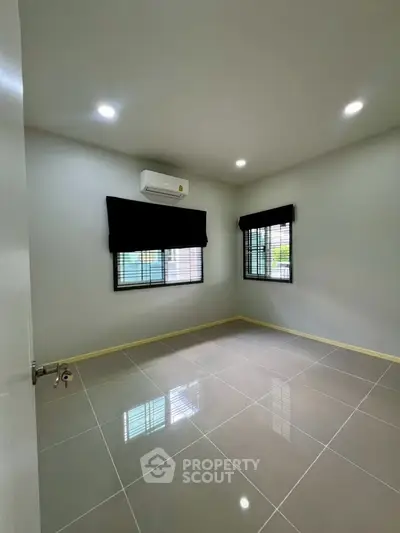 Spacious empty bedroom with modern tile flooring and air conditioning, ready for customization.