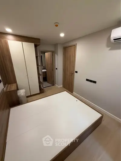 Modern bedroom with wooden accents and built-in storage, featuring a minimalist design.