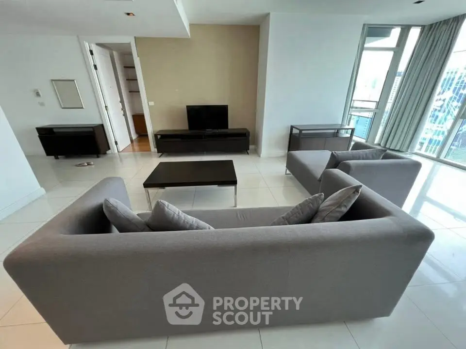 Spacious modern living room with sleek furniture and large windows offering city views.