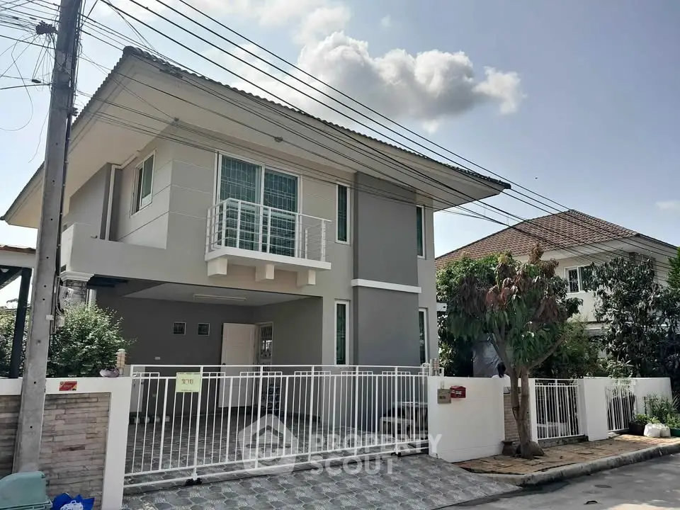 Modern two-story house with gated driveway and contemporary design in a suburban neighborhood.