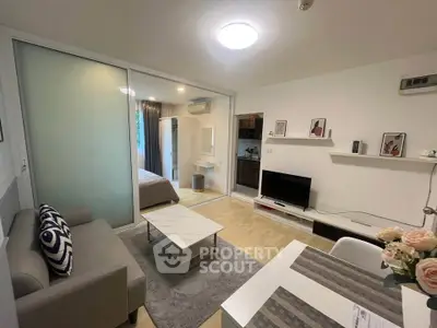 Modern open-plan living room with stylish decor and sliding glass doors leading to a cozy bedroom.