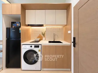 Modern compact kitchen with integrated washing machine and sleek wooden cabinetry.