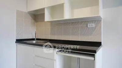 Modern minimalist kitchen with sleek black countertop and ample storage space.