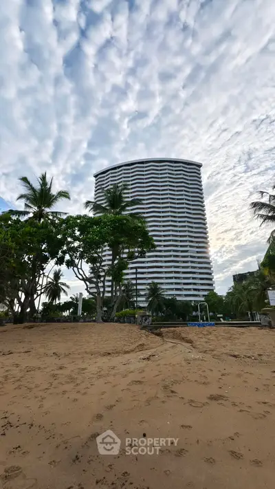 Stunning beachfront high-rise building with lush greenery and sandy shores.