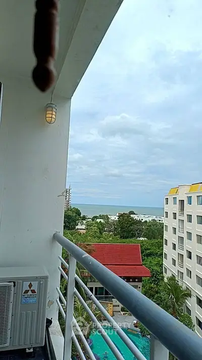 Stunning balcony view overlooking pool and ocean, perfect for relaxation.