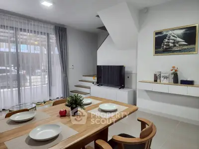 Modern living room with dining area and staircase, featuring elegant decor and natural light.
