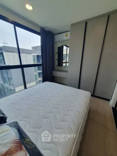 Modern bedroom with large window and built-in wardrobe in urban apartment